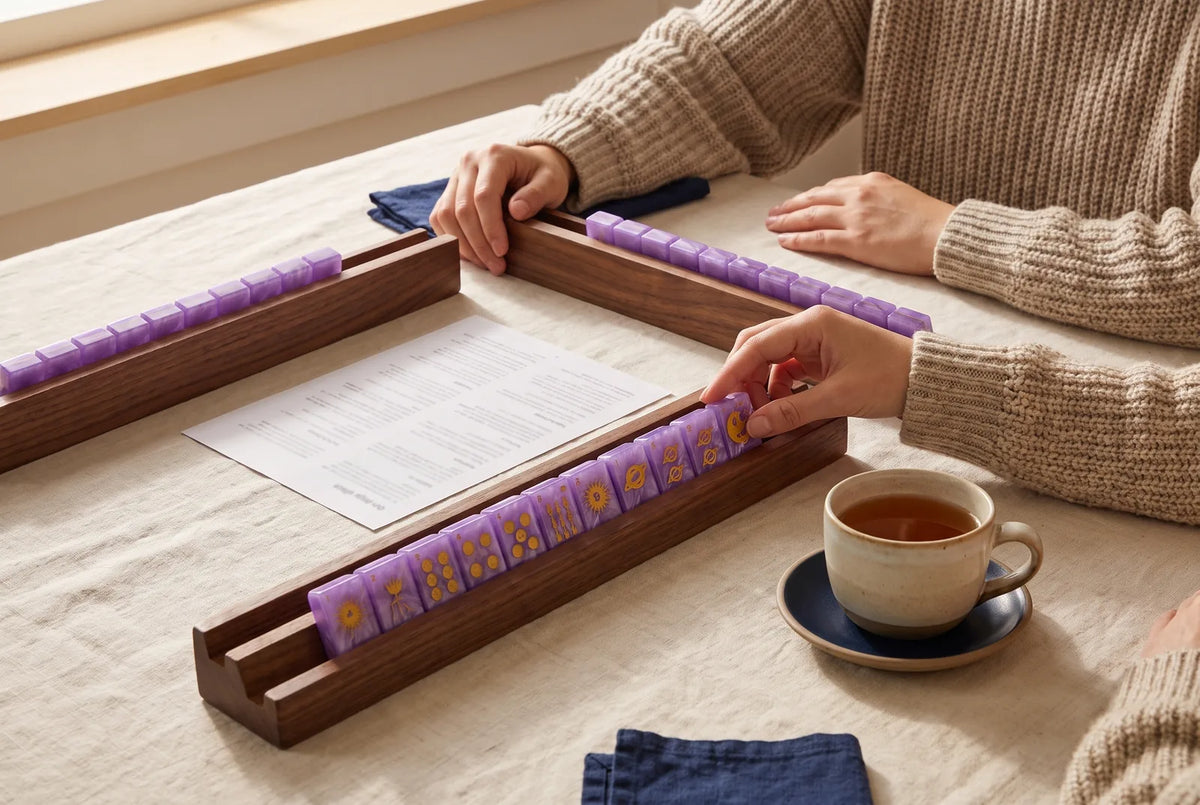 A printed sheet next to two racks of purple mahjong tiles and a cup of tea