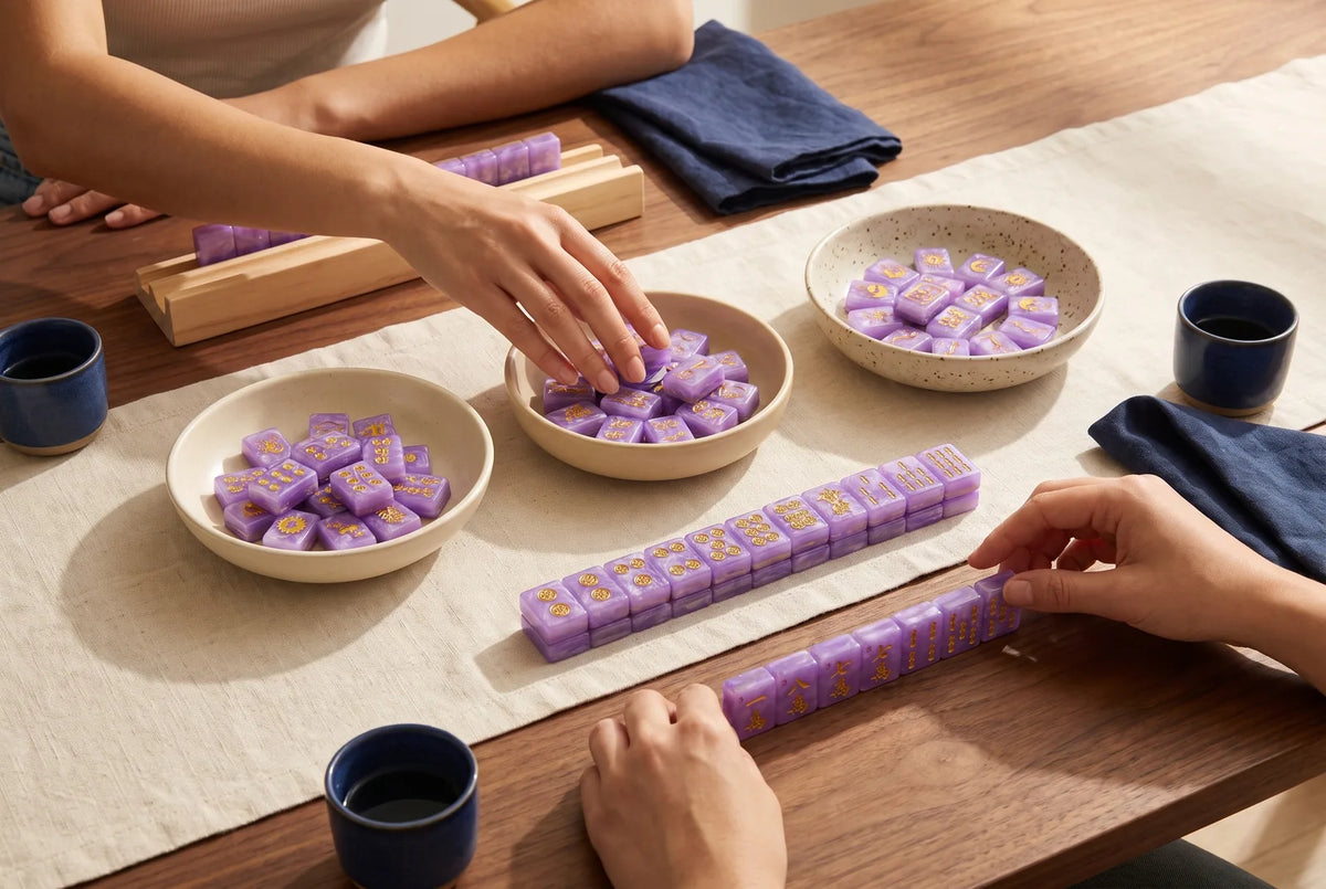 Three small bowls of sorted mahjong tiles, one for each suit, with more tiles in front